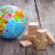 Miniature globe and boxes on wooden background